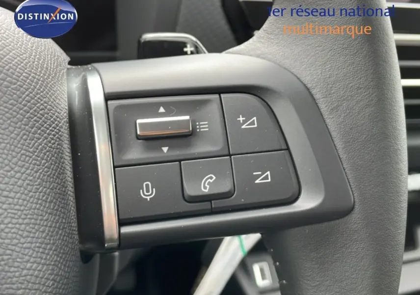 Gros plan sur les commandes du volant en cuir noir d'une Citroën C4 blanche, avec boutons de volume et téléphone.