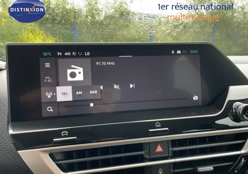 Écran tactile central du tableau de bord de la Citroën C4 blanc métal, affichant la radio FM à 91,7 MHz.