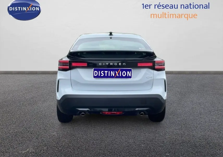 Vue arrière d'une Citroën C4 PureTech 130ch EAT8 Plus blanche métallisée avec bande noire distinctive sur le hayon.