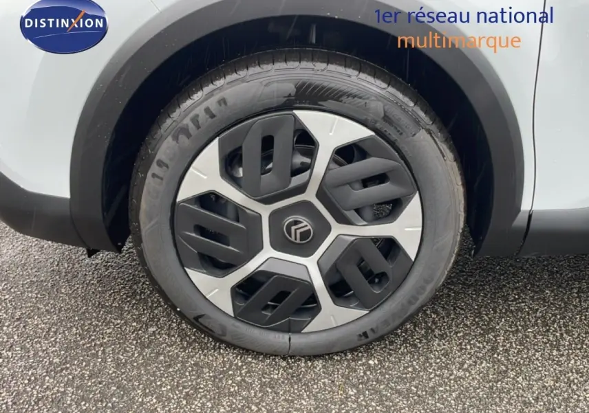 Gros plan sur la roue avant droite d'une Citroën C4 blanche métal 2026 avec jante au design moderne bicolore.