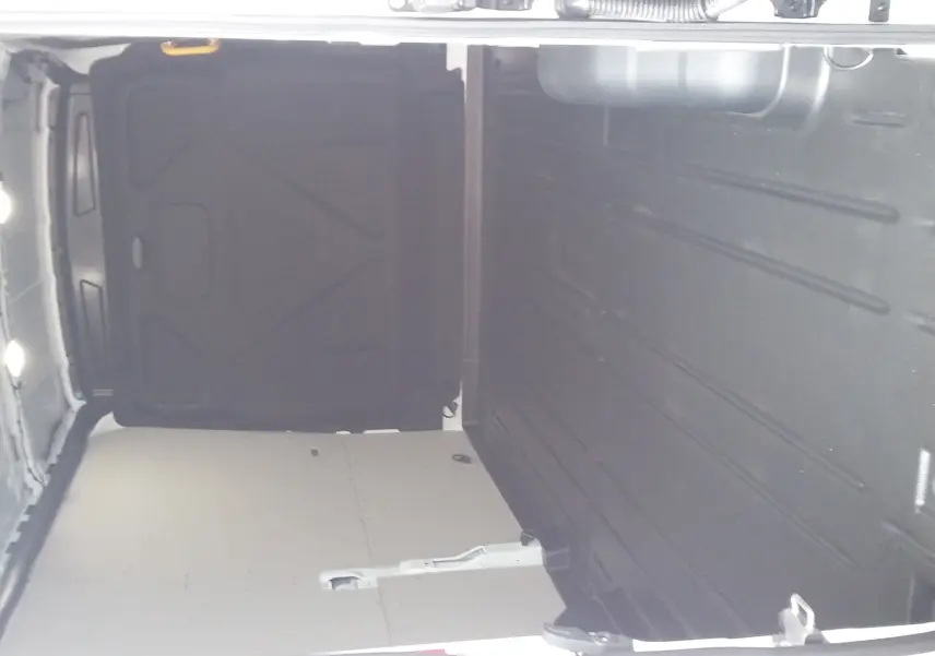 Intérieur du fourgon Ford Transit T350 blanc glacier, vue de l'espace de chargement vide avec parois latérales et plancher protégés.