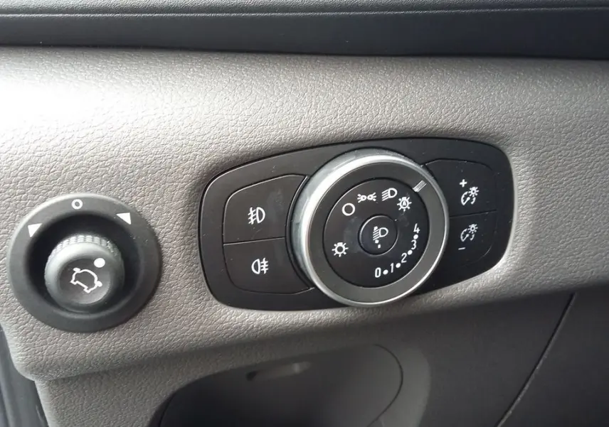 Gros plan sur les commandes d'éclairage et réglage des phares du Ford Transit Fourgon blanc Glacier 2022.