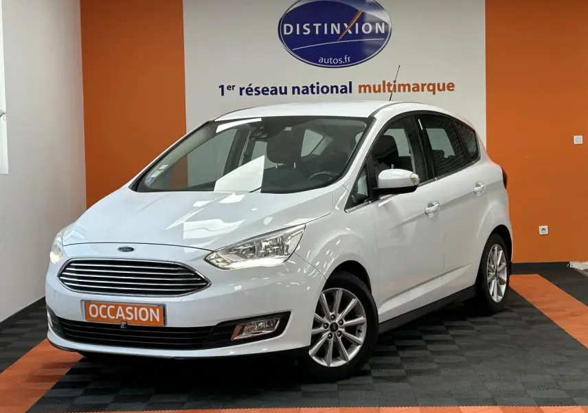 Ford C-MAX blanc en 3/4 avant droit, avec calandre chromée et jantes alliage 16 pouces dans un showroom.