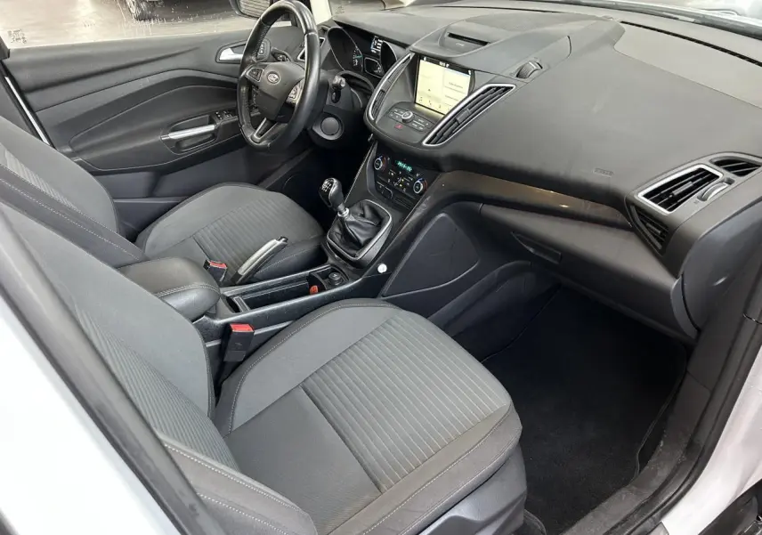 Vue intérieure côté conducteur du Ford C-MAX blanc 2018, avec tableau de bord et écran tactile SYNC 3 visible.