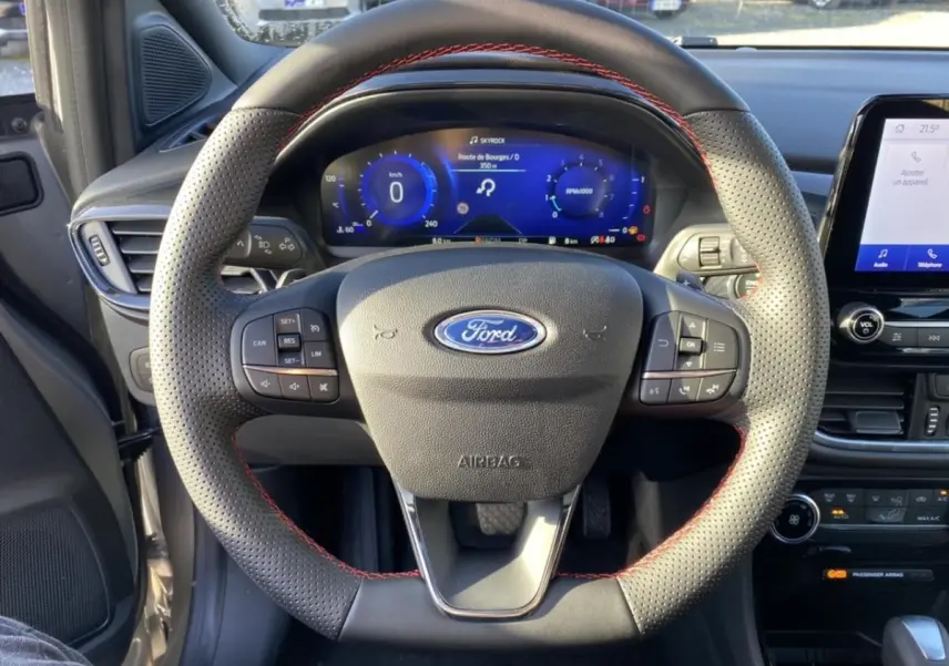 Vue centrée du volant perforé avec surpiqûres rouges et tableau de bord numérique du Ford Puma gris 2021 ST Line.