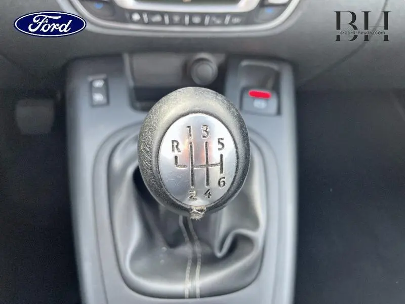 Gros plan sur le pommeau de levier de vitesse manuel noir avec marquage des vitesses en argent, intérieur sombre.