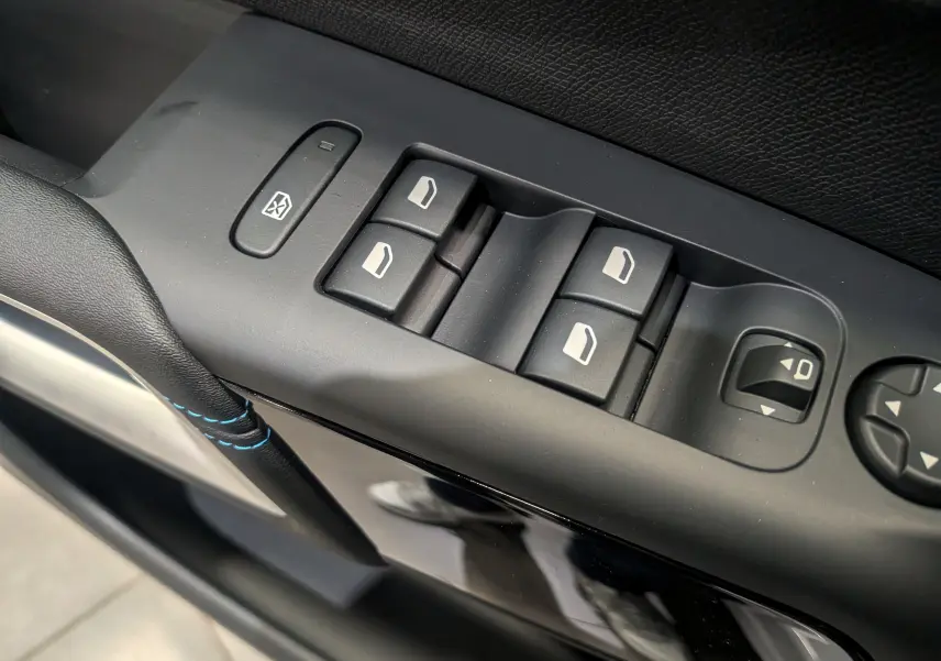 Gros plan sur les commandes des vitres électriques et rétroviseurs côté conducteur du Citroën C5 Aircross hybride 2025.