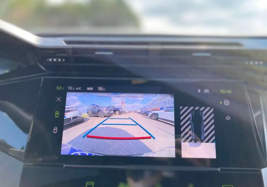 Écran central de la Peugeot 308 GT 2025 montrant la caméra de recul avec vue arrière sur un parking en gris selenium.
