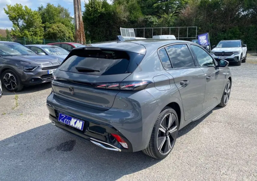 Peugeot 308 GT gris selenium vue 3/4 arrière droit, avec feux arrière fins et jantes alliage distinctives.