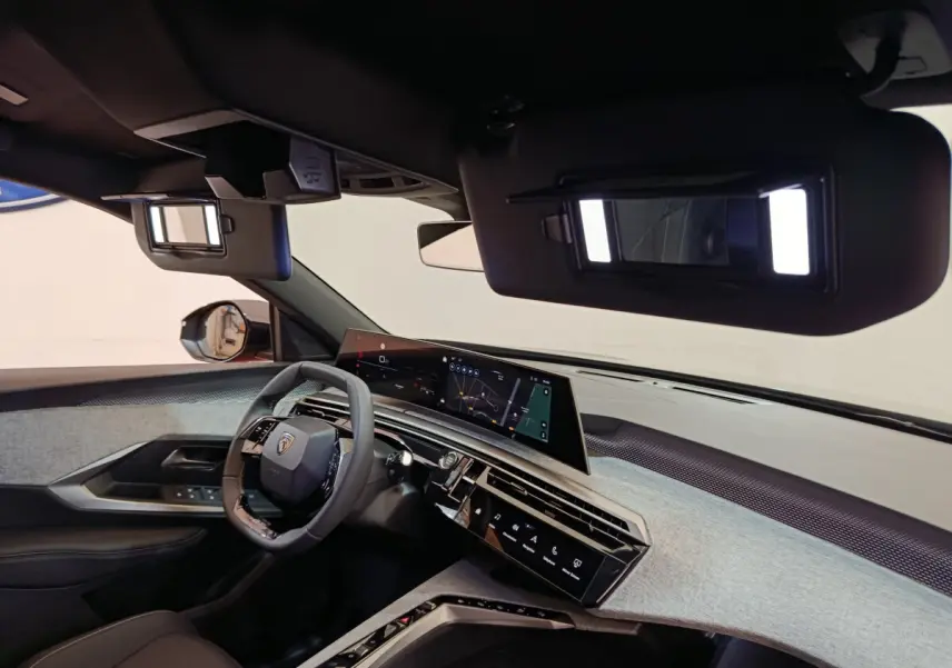 Vue intérieure du poste de conduite du Peugeot 3008 1.2 Hybrid 145 GT, avec tableau de bord numérique et volant cuir noir.