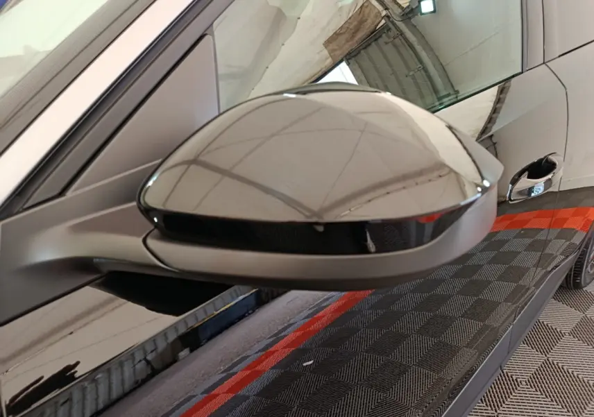 Gros plan sur le rétroviseur côté gauche d’un Peugeot 3008 noir, avec reflet du plafond et poignée de porte visible.