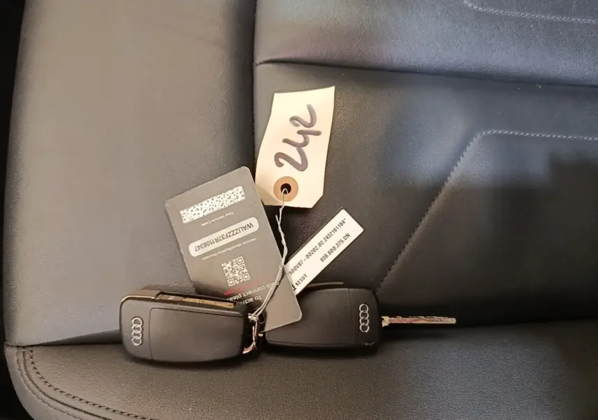 Gros plan sur deux clés Audi posées sur une sellerie cuir noire, avec étiquette numérotée visible.