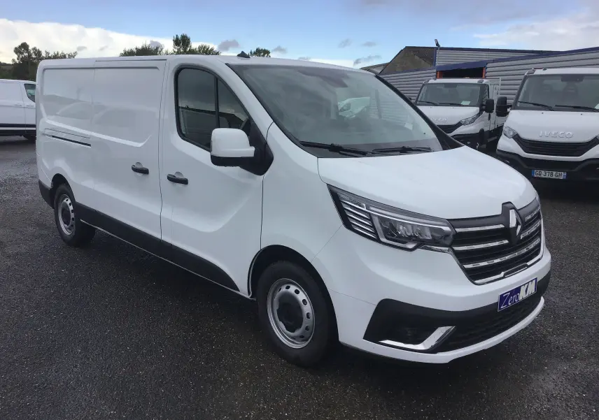 Renault Trafic Fourgon blanc en 3/4 avant droit, avec calandre noire et phares LED distinctifs.