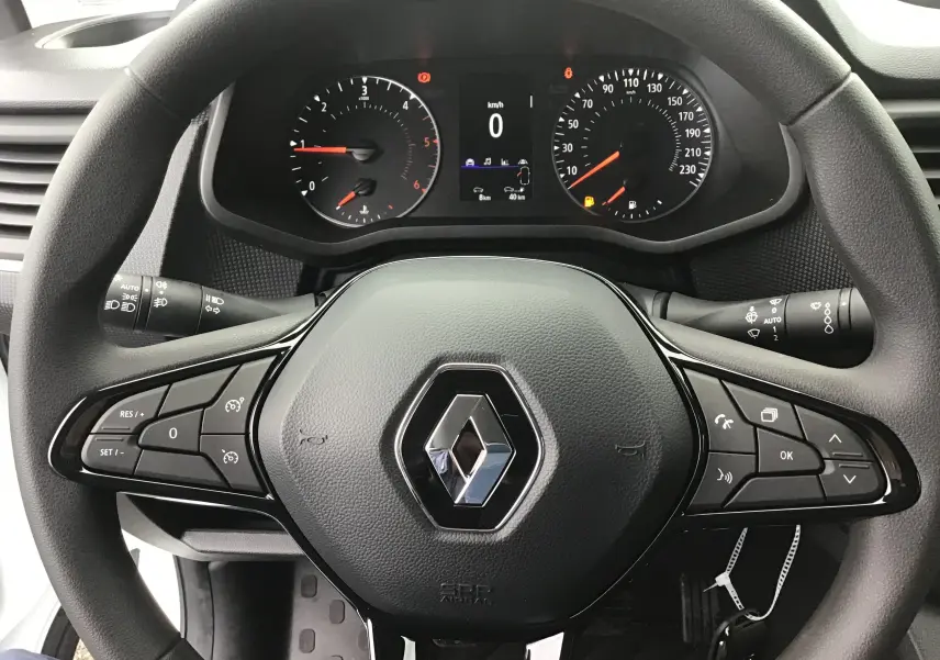Vue rapprochée du volant noir de Renault Trafic Fourgon 2023 avec commandes intégrées et tableau de bord digital.