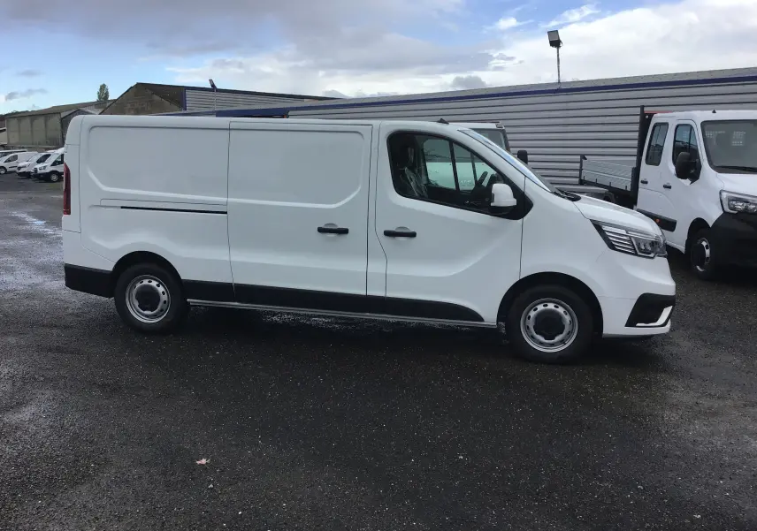 Renault Trafic Fourgon blanc en vue de profil côté gauche, avec portes coulissantes et jantes acier noires.