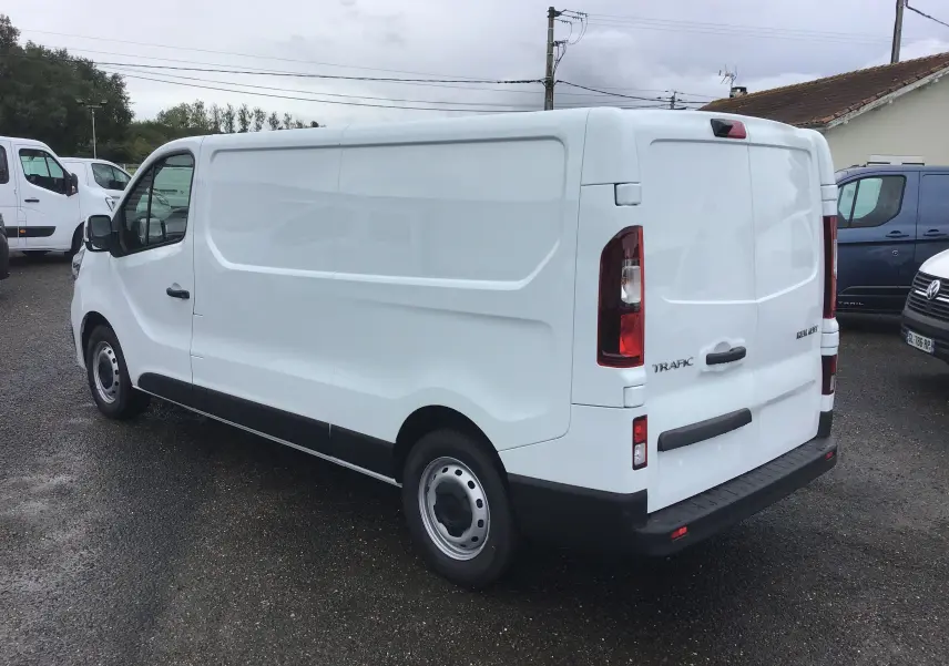 Renault Trafic Fourgon blanc en vue 3/4 arrière droit, avec portes arrière fermées et caméra de recul visible.