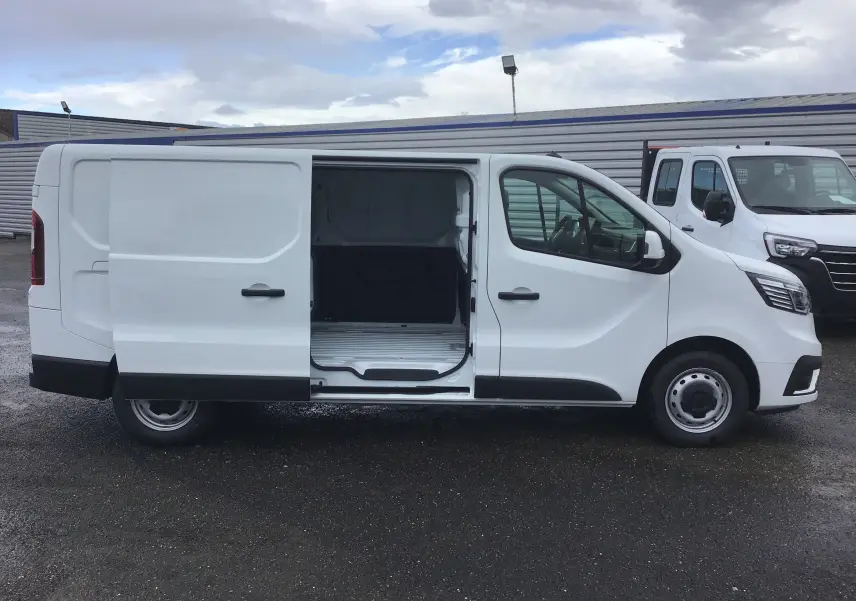 Renault Trafic Fourgon blanc en profil droit avec porte latérale coulissante ouverte montrant l’espace de chargement.