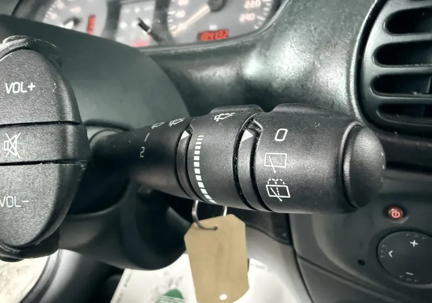 Gros plan sur la commande d'essuie-glace à droite du volant d'une Renault Mégane verte, tableau de bord en arrière-plan.