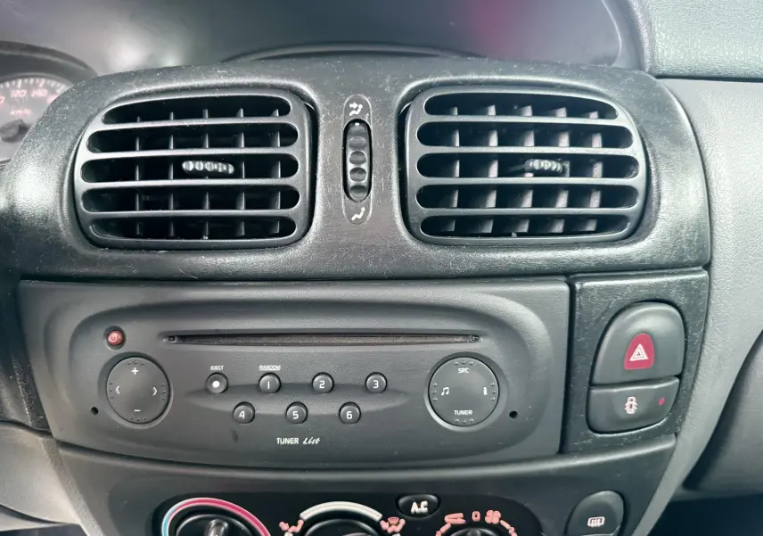 Vue rapprochée du tableau de bord noir de la Renault Mégane 1.6 i 110ch de 2000, avec commandes radio et ventilation.