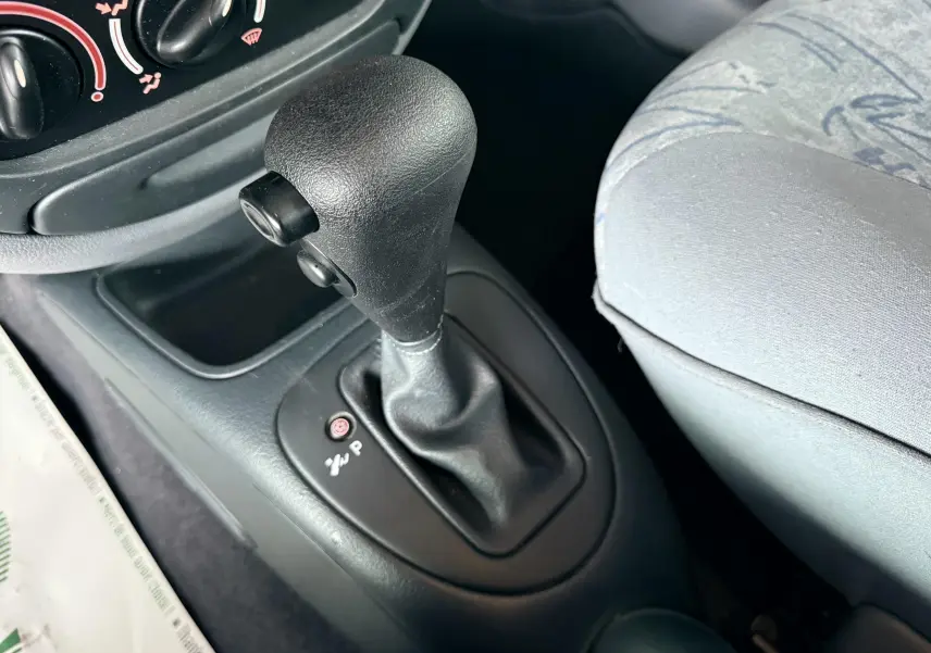 Gros plan sur le levier de vitesse automatique noir et la console centrale, siège avant gris clair visible à droite.