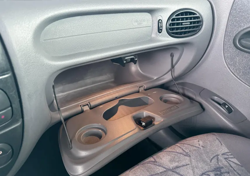 Vue intérieure côté passager de la Renault Mégane 2000 avec boîte à gants ouverte et porte-gobelets intégrés.