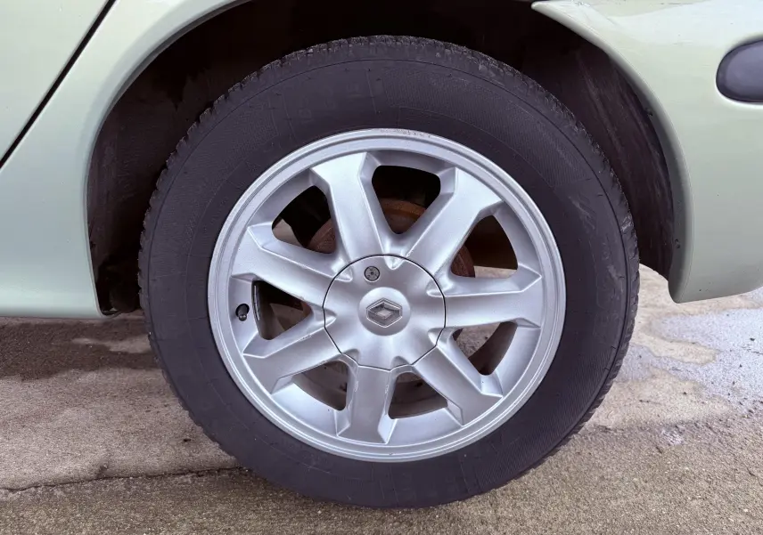 Gros plan sur la roue avant droite d’une Renault Mégane verte, avec jante alliage argentée et logo Renault central.