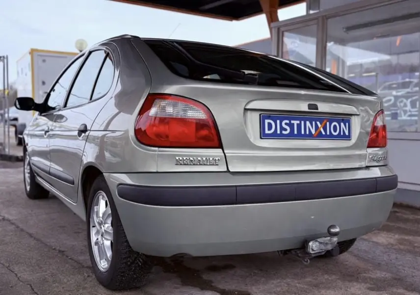 Vue 3/4 arrière droite d'une Renault Mégane argent avec attelage et hayon fermé sous abri.