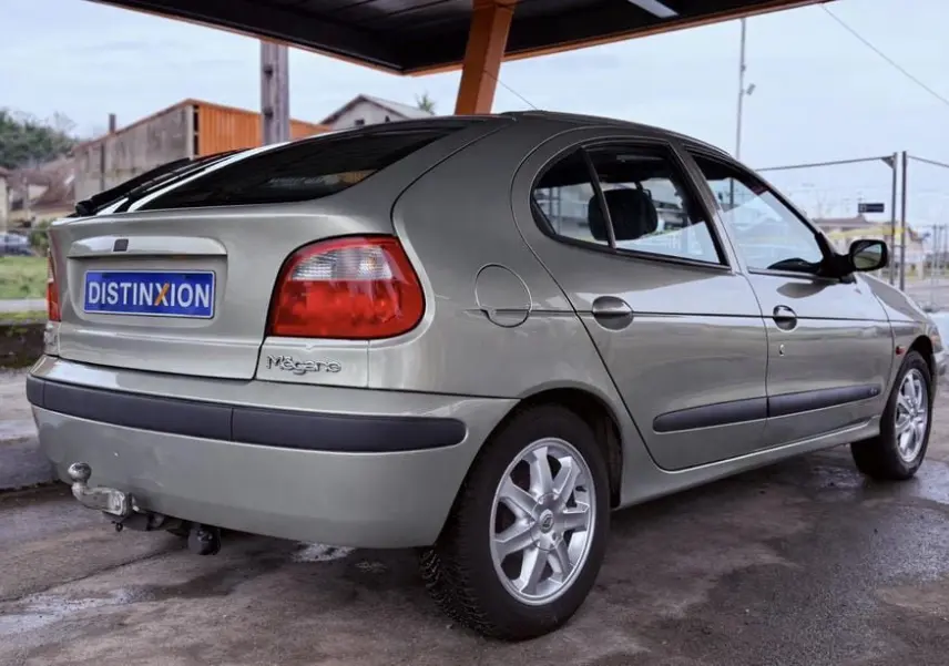 Vue 3/4 arrière droite d'une Renault Mégane gris clair cinq portes avec attelage et jantes alliage.