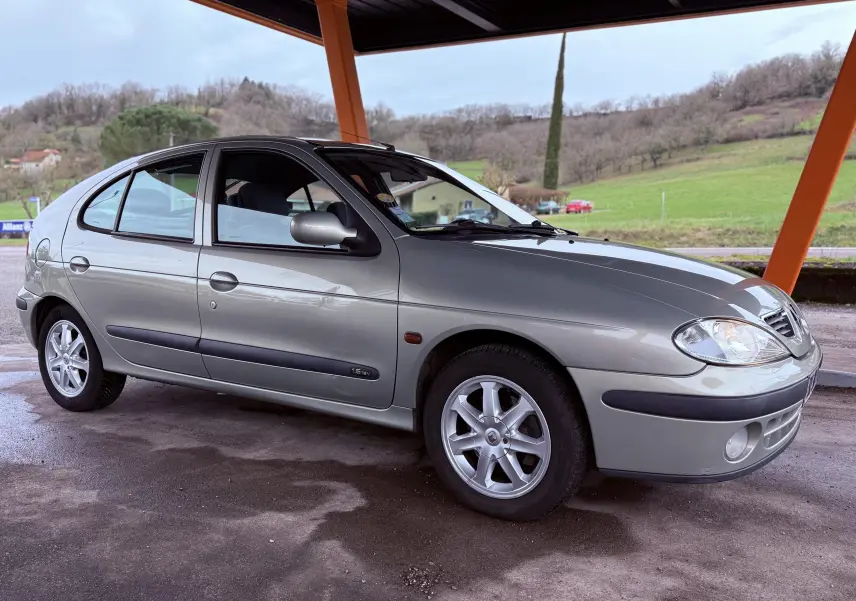 Vue 3/4 avant droit d'une Renault Mégane grise 5 portes avec jantes alliage sous un abri en extérieur.