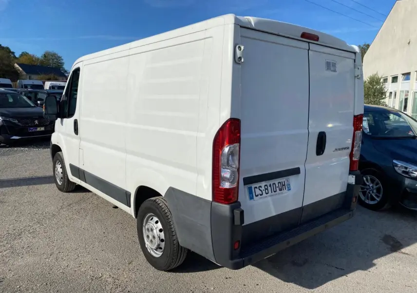 Vue 3/4 arrière droite d'un utilitaire blanc Citroën Jumper 2013 avec attelage et plaques françaises.