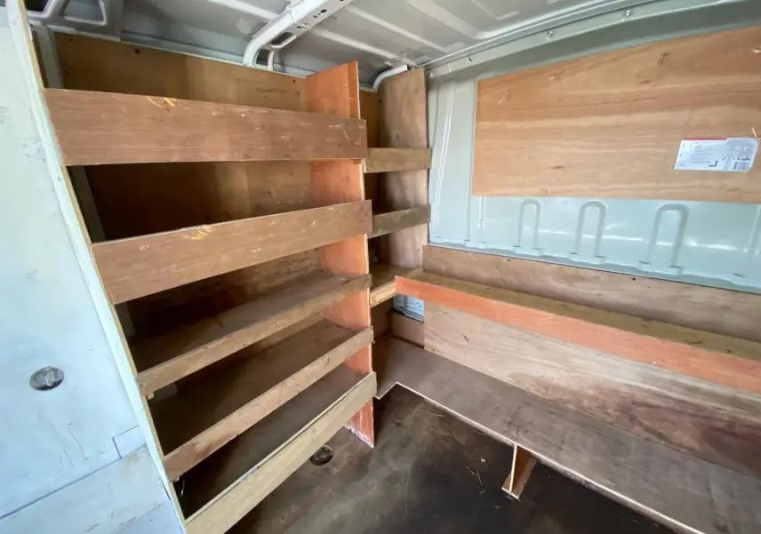 Intérieur du fourgon blanc Citroën Jumper 2013, vue en angle montrant les étagères en bois et le revêtement mural.