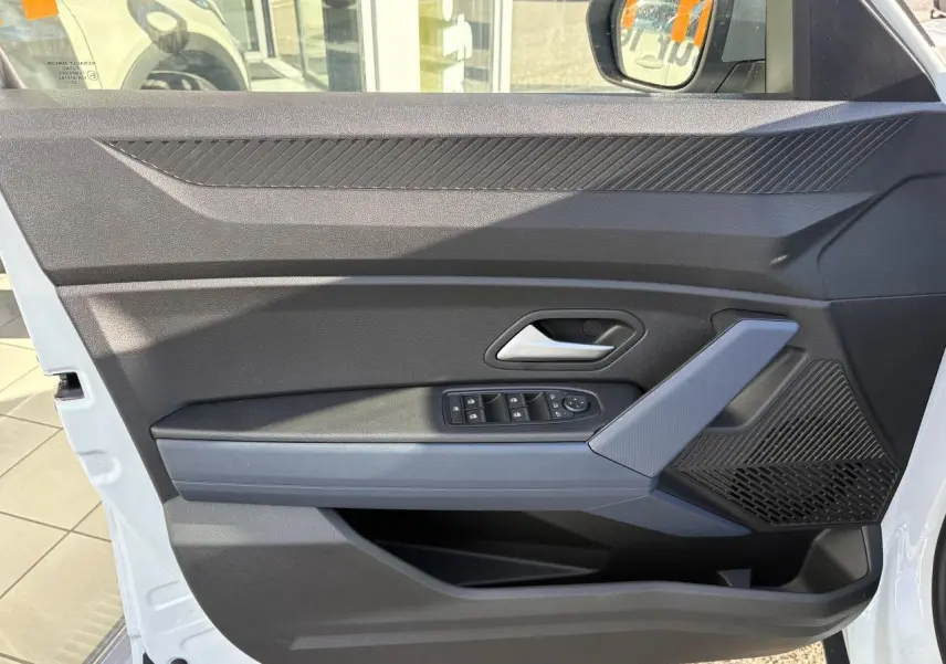 Vue rapprochée de la porte avant gauche blanche du Dacia Duster 2024 avec commandes électriques et accoudoir gris Denim.