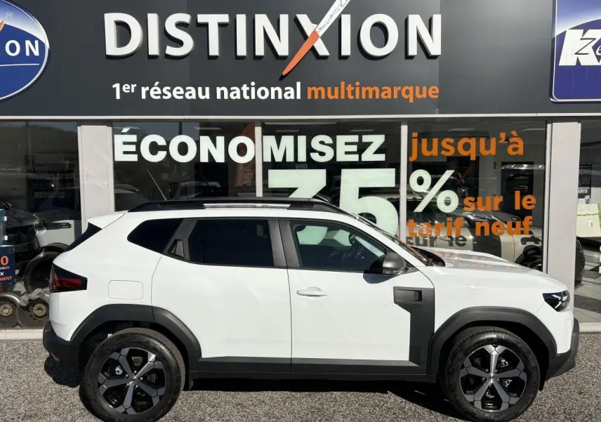 Profil droit du Dacia Duster 1.6 Hybrid blanc métallisé avec barres de toit noires et jantes alliage 18 pouces.