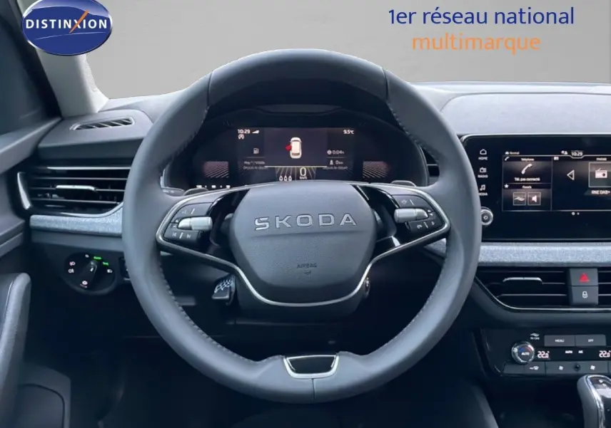 Vue intérieure centrée sur le volant SKODA du KAMIQ, tableau de bord numérique et écran tactile visibles.