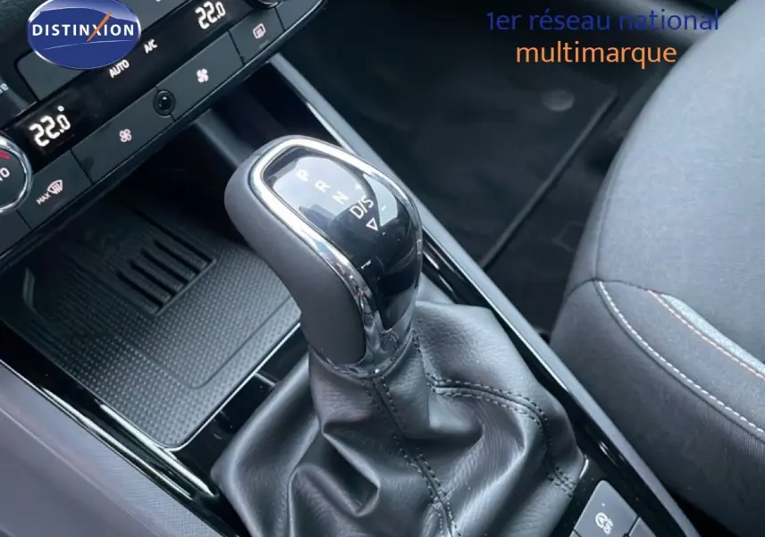 Gros plan sur le levier de vitesse automatique du Skoda Kamiq gris graphite, avec console centrale et siège tissu gris partiellement visibles.