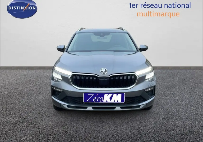 Vue frontale d'un Skoda Kamiq gris graphite métallisé avec phares LED allumés sur fond neutre.