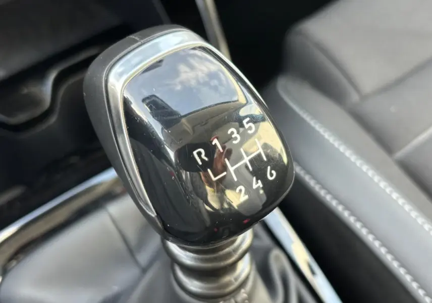 Gros plan sur le levier de vitesses manuel noir de la Citroën C3 Turbo 100 ch, intérieur cuir gris visible en arrière-plan.