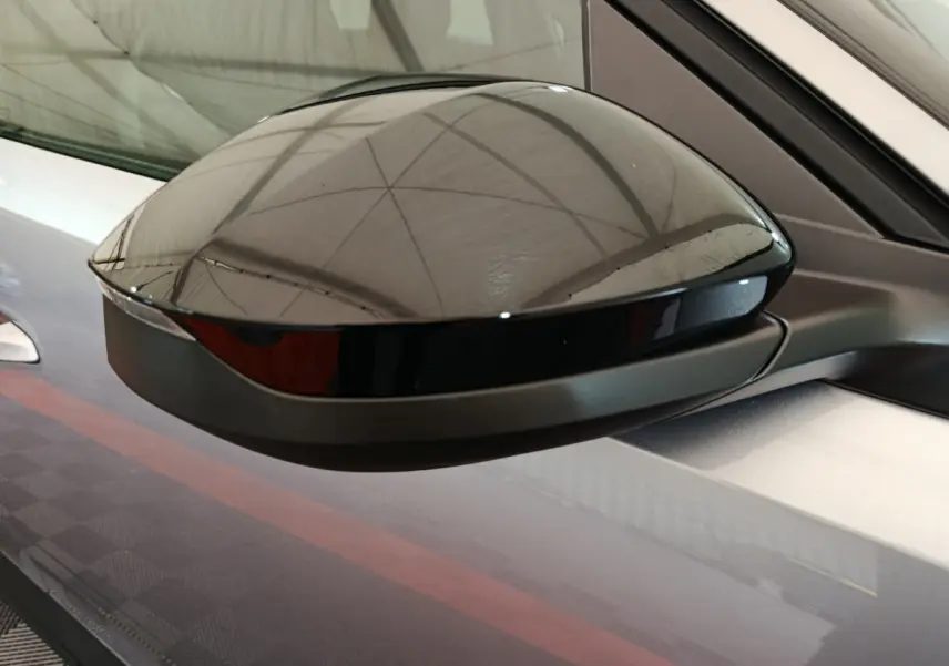 Rétroviseur noir brillant côté gauche sur Peugeot 3008 gris clair, vue rapprochée en intérieur d'atelier.