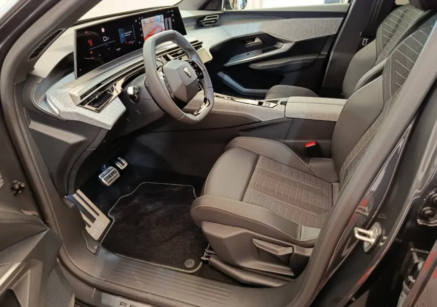 Intérieur avant droit du Peugeot 3008 gris clair 2025, tableau de bord numérique large et sièges en tissu cuir gris.