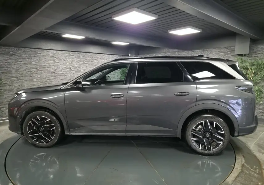 Peugeot 5008 gris métallisé vue de profil côté gauche, avec jantes alliage 19'' noires et barres de toit.