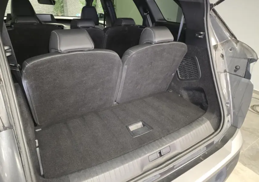 Coffre ouvert du Peugeot 5008 gris 2025, montrant la banquette arrière rabattue et l'intérieur noir.