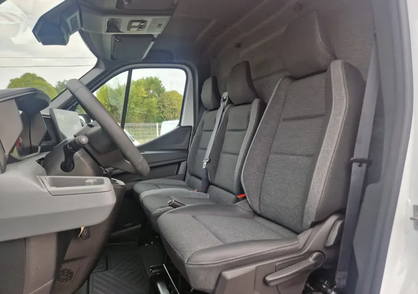 Vue intérieure côté conducteur du Renault Master blanc 2026, montrant les trois sièges avant gris avec ceintures intégrées.