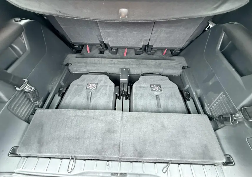 Vue plongeante sur le coffre arrière du Peugeot 5008 gris, montrant les sièges arrière rabattus et l'espace de chargement.