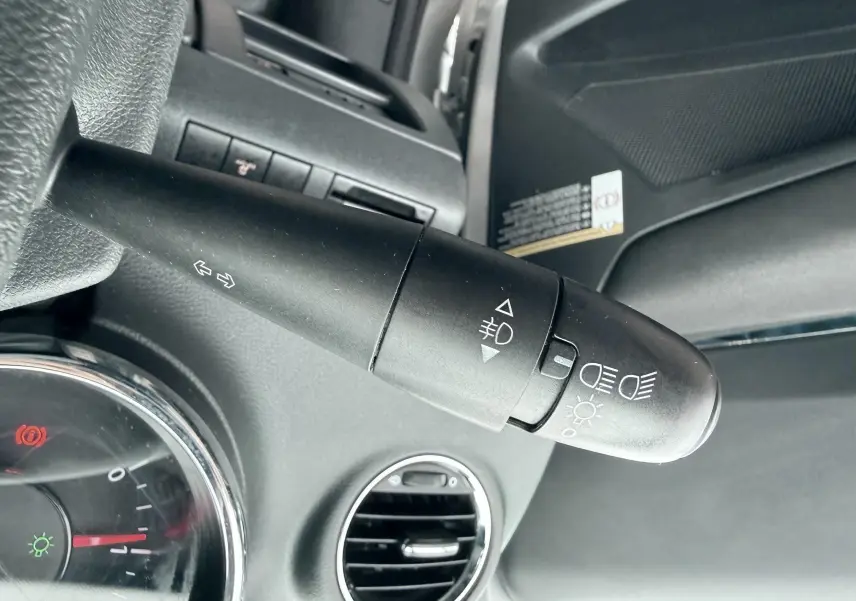 Gros plan sur la commande des phares et clignotants à gauche du volant dans l’habitacle gris d’un Peugeot 5008.