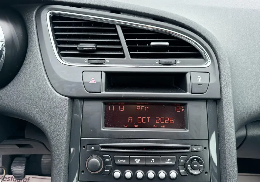 Vue rapprochée du tableau de bord gris du Peugeot 5008 avec affichage digital rouge et commandes radio.