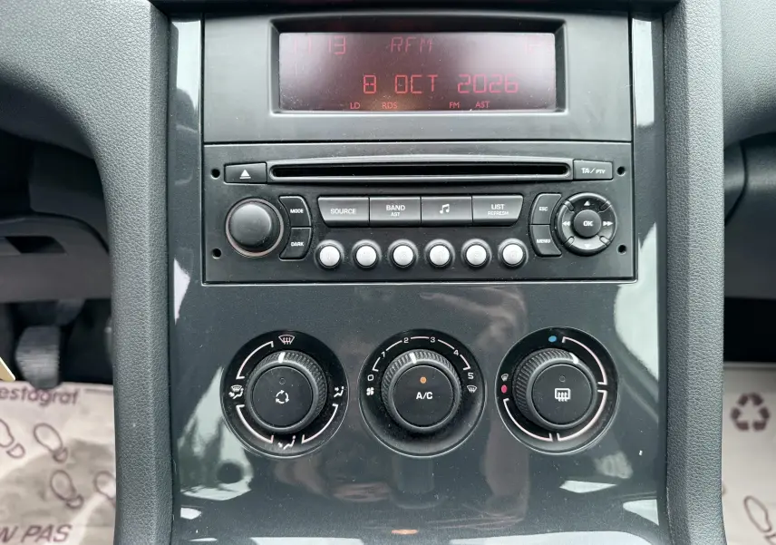 Vue rapprochée de la console centrale noire du Peugeot 5008 2010 montrant l’autoradio et les commandes de climatisation.