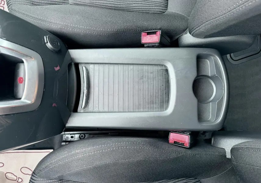 Vue plongeante sur la console centrale grise entre les sièges avant en tissu gris du Peugeot 5008 2010.