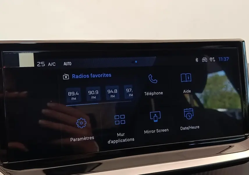Écran tactile central de la Peugeot 208 électrique 2024 affichant les radios favorites et options connectées.