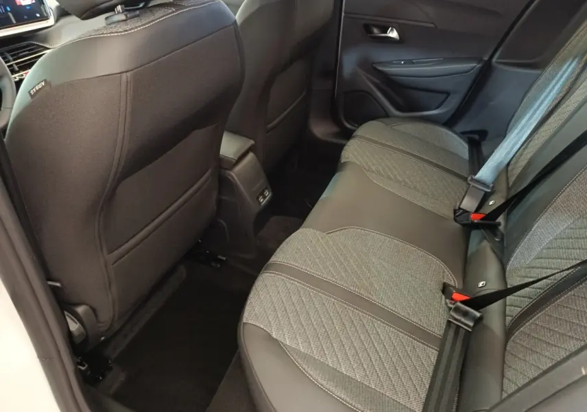 Vue intérieure arrière côté droit de la banquette grise et noire de la Peugeot 208 électrique 2024, avec ceintures de sécurité visibles.