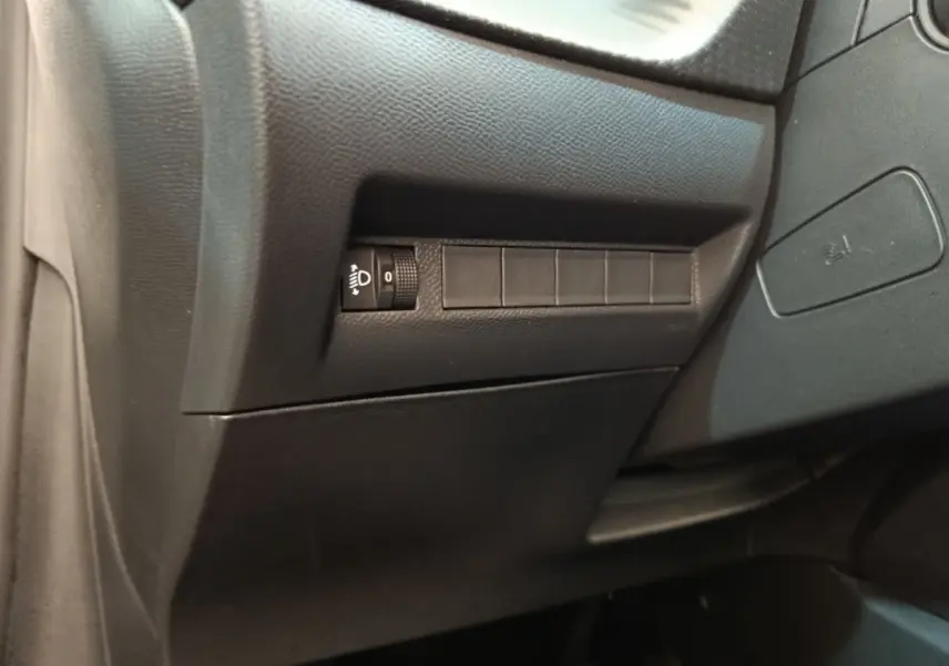 Détail intérieur côté conducteur du tableau de bord noir de la Peugeot 208 électrique blanche 2024.